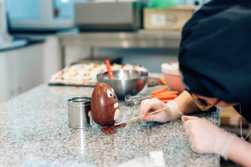 chocolate professional prepares an easter egg in the shape of an easter bunny in the kitchen...