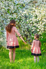 mother and daughter are walking through the blooming garden