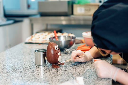chocolate professional prepares an easter egg in the shape of an easter bunny in the kitchen workshop