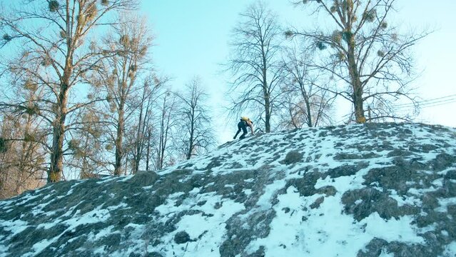 Muscular man with a naked torso with a ballon compressed air drager on his back and full face mask climbs a snowy hill