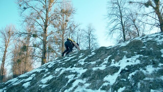 Bodybuilder with a naked torso with a ballon compressed air drager on his back and in full face mask climbs a snowy hillside