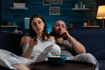 POV of woman and man switching channels with TV remote control, finding fun movie to watch for entertainment. Girlfriend and boyfriend doing film selection to relax with leisure activity.