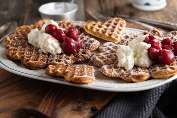 Homemade waffles with whipped cream and sour cherry compote
