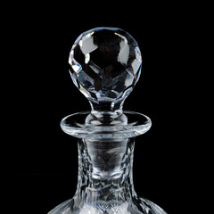 antique glass decanter with geometric pattern. glass faceted lid from gcarafe close-up on a black isolated background