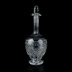 antique glass decanter with geometric pattern. retro decanter for alcohol on a black isolated background. engraved vintage decanter