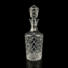 antique glass decanter with geometric pattern. retro decanter for alcohol on a black isolated background. engraved vintage decanter