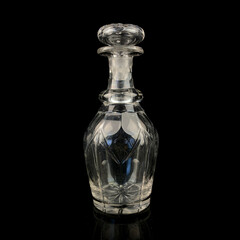 antique glass decanter with geometric pattern. retro decanter for alcohol on a black isolated background. engraved vintage decanter