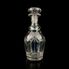 antique glass decanter with geometric pattern. retro decanter for alcohol on a black isolated background. engraved vintage decanter