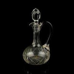 antique glass decanter with geometric pattern. retro decanter for alcohol on a black isolated background. engraved vintage decanter
