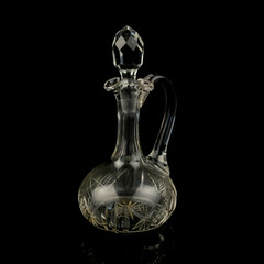 antique glass decanter with geometric pattern. retro decanter for alcohol on a black isolated background. engraved vintage decanter