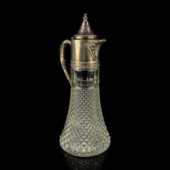 antique glass decanter with a metal figured neck. retro decanter for alcohol on a black isolated...