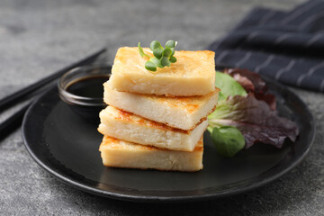 Delicious turnip cake with herbs served on grey table, closeup
