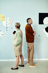 Vertical shot of senior man and woman visiting contemporary art exhibition in modern museum