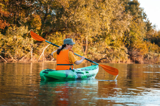 Kayaking on the river. A young woman in a life jacket is floating in a kayak on the river. Back view. Autumn season. Concept of World Tourism Day