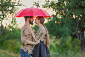 couple outdoors under a red umbrella