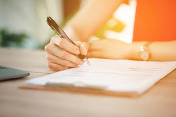 Close-up of business woman's hands writing on paper in office
