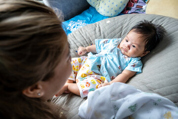 Asian newborn baby kid eye contact with mom cuteness of children with happy family on soft mattress metaphor living life healthy lifestyle cute of kid baby products health products for mother and baby