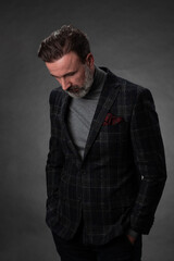 Fototapeta premium Portrait of a stylish elegant senior businessman with a beard and casual business clothes in photo studio isolated on dark background gesturing with hands