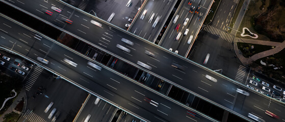Aerial top down of multilevel elevated road huge traffic junction in modern metropolis city. Night long exposure motion blur of vehicles. Modern development of infrastructure and motorways in China.