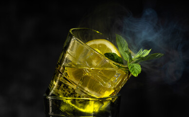 Cocktail with ice, fresh mint and a fresh slice of lemon on a dark background. Cocktails.