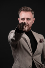 Portrait of a stylish elegant senior businessman with a beard and casual business clothes in photo studio isolated on dark background gesturing with hands