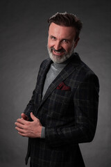 Portrait of a stylish elegant senior businessman with a beard and casual business clothes in photo studio isolated on dark background gesturing with hands