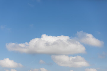 Blue sky background with few white cumulus clouds of various sizes