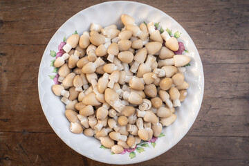 Coprinus comatus in a bowl wash and clean get ready to cook of stir-fried mushrooms with oyster sauce is delicious Asian food on wooden table.