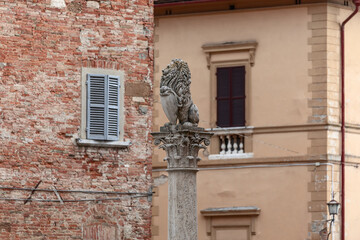 A marble replica of a florentine lion at the top of the Marzocco column in Piazza Savonarola, Montepulciano, Tuscany, Italy