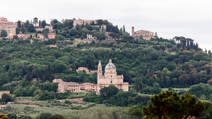 Fototapeta na wymiar Sanctuary of the Madonna di San Biagio surrounded by forest and Montepulciano town behind on the hill, Siena, Italy 