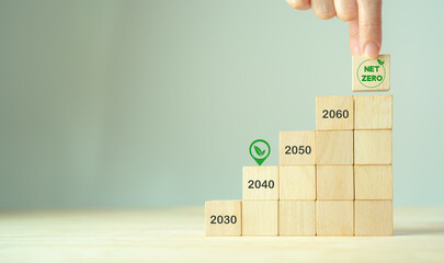 Net zero by 2040. Carbon neutral. Sustainalble development. Successful execution of green business. Goal checked in 2040. Go green company culture. Hand puts wooden cube with net zero icon, copy space