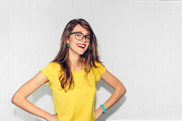 Blonde with long hair, beautiful smile and even teeth. An eccentric young smart woman in glasses and a bright yellow shirt smiles with perfect teeth. Studio portrait of hipster fashion. - obrazy, fototapety, plakaty