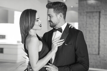 Happy rich woman holding sexy boyfriend in tuxedo black and white