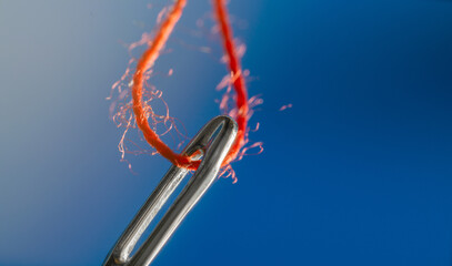 Red thread in the eye of a needle macro
