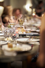 A glass of white wine stands on the festive table, soft focus