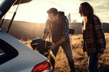Couple preparing for a hiking as they taking their backpacks out of the trunk of the car. © Zoran Zeremski