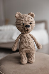 Knitted teddy bear in the bright interior of the room