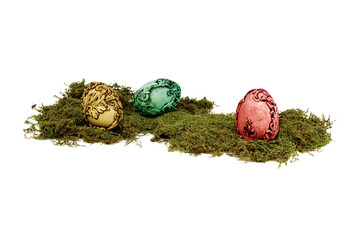 Three unusual colourful vintage Easter eggs lying on moss. Easter eggs isolated on white background.