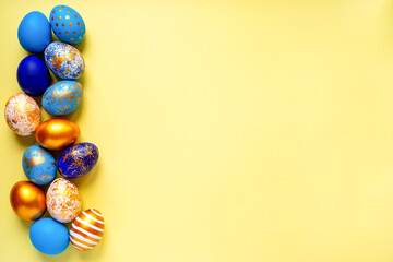 colored golden, blue, light blue Easter eggs on a yellow background for Easter