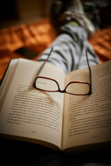 Libro abierto en el regazo con gafas sobre la cama