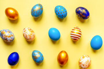 colored golden, blue, light blue Easter eggs on a yellow background for Easter