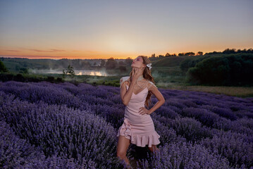 Woman in lavender flowers field at sunset in purple dress. France, Provence.