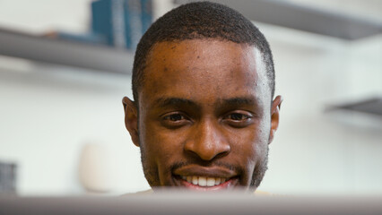 Smiling man receiving news chatting on the internet using laptop. Young man with laptop