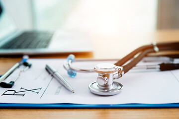 Stethoscope with clipboard and laptop on docotr desk