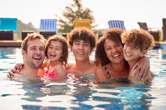 Portrait Of Family Having Fun In Swimming Pool On Summer Vacation