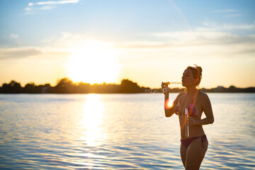 Woman in a swimsuit blowing soap bubbles walking along the beach near the lake on summer vacation