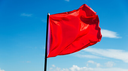 Red flag waving against blue sky