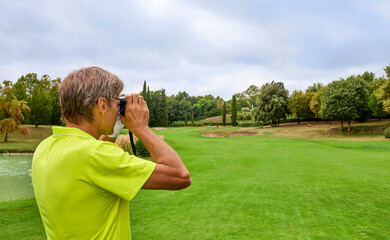 The golfer accurately measures the distance to the flag in a golf course with the laser...