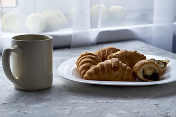 a plate of croissants and a cup of coffee on the table