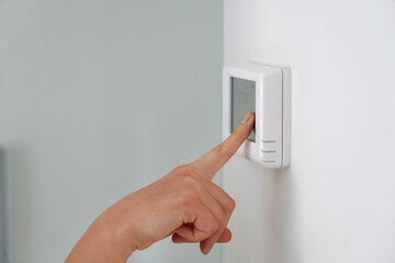 Saving energy concept: human hand turning down temperature on digital display